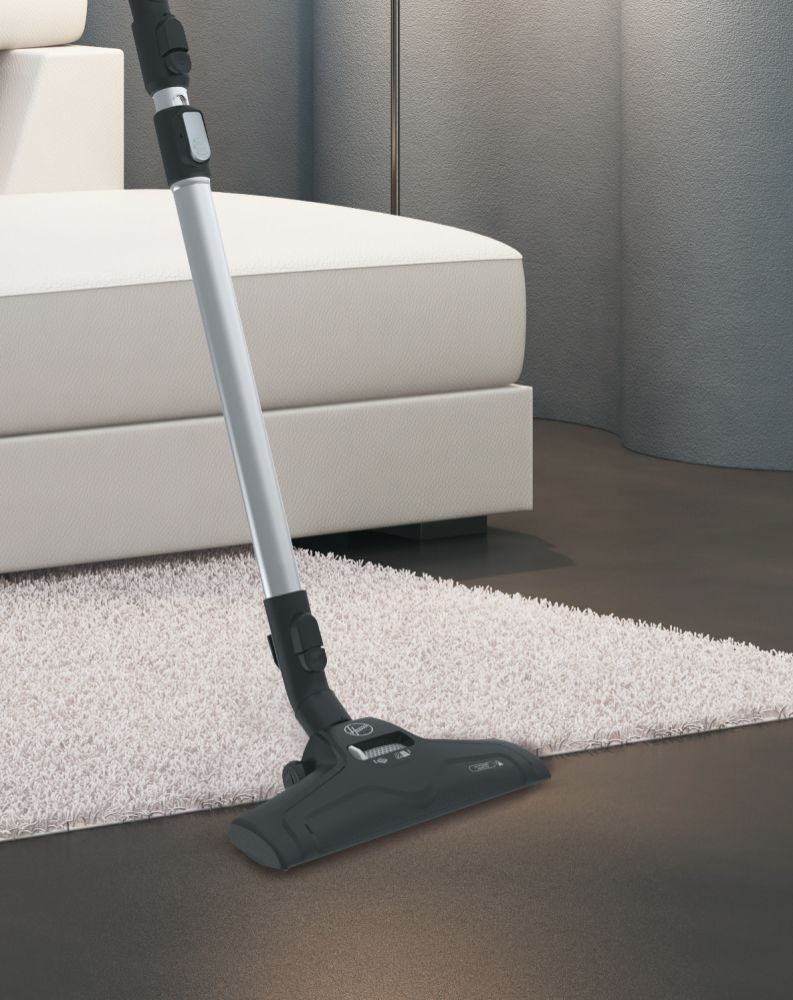 Ein Staubsauger auf einem dunklen Boden. Der Staubsauger ist silber und schwarz, mit weißem Teppich im Hintergrund.