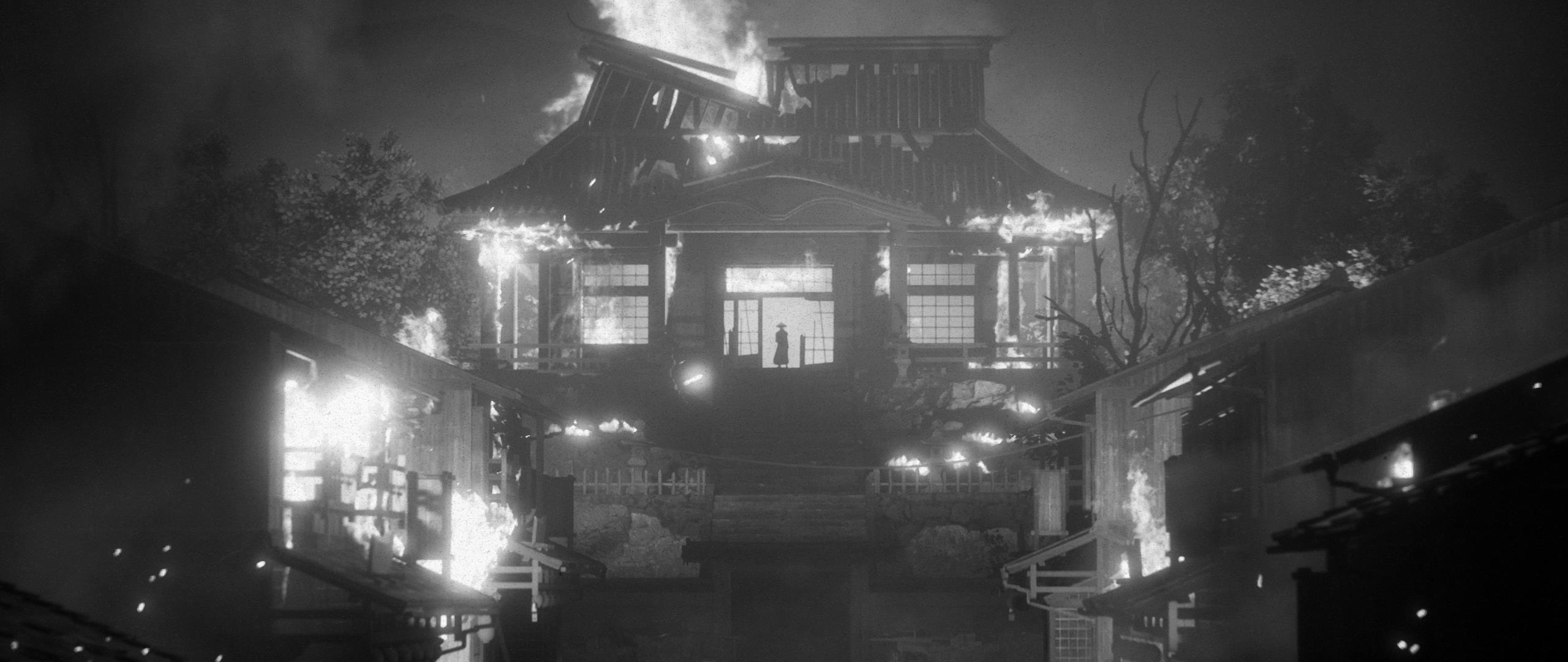 Schwarz-Weiß-Bild eines brennenden traditionellen japanischen Gebäudes. Flammen verschlingen die Struktur.