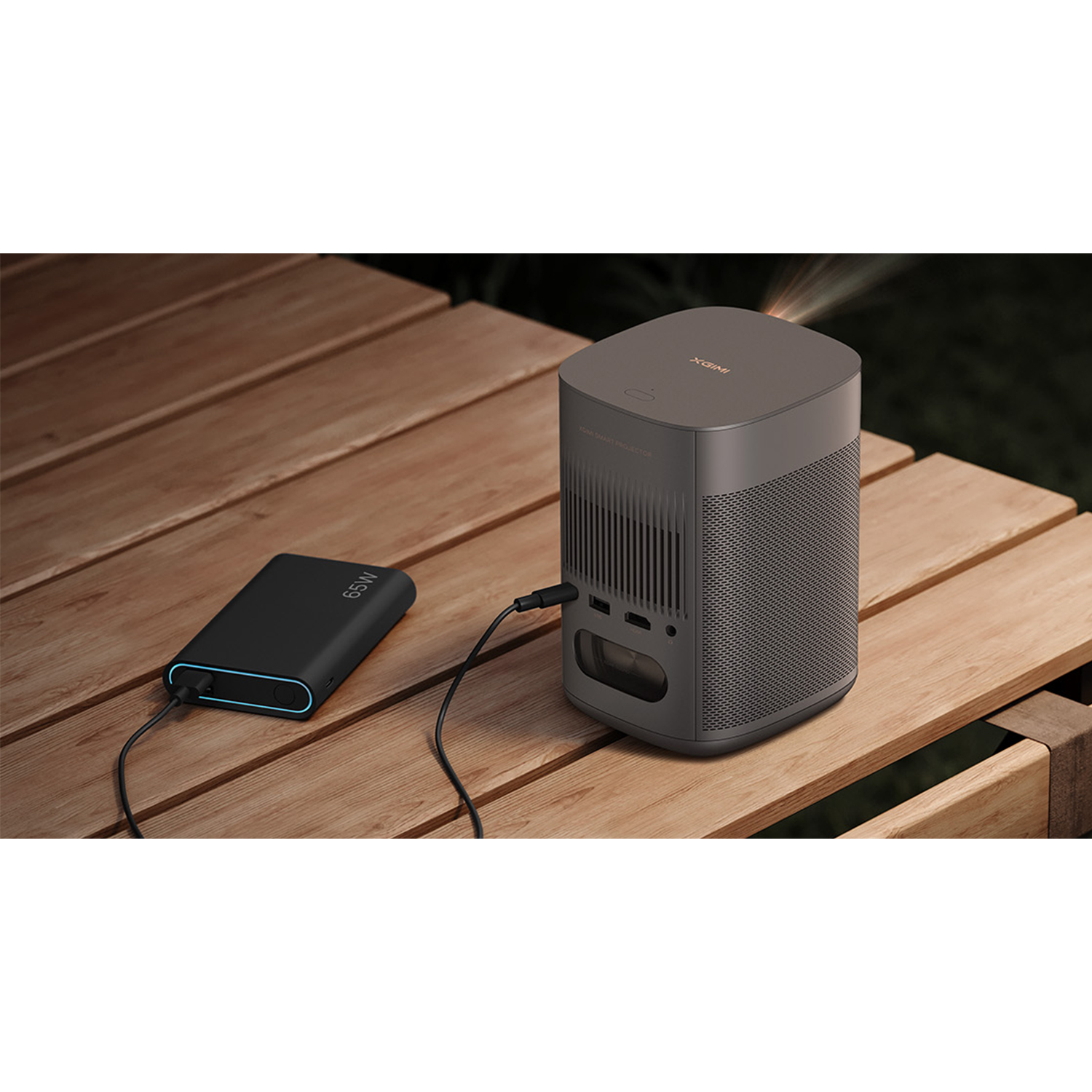 Un proiettore grigio e un power bank nero su un tavolo di legno.