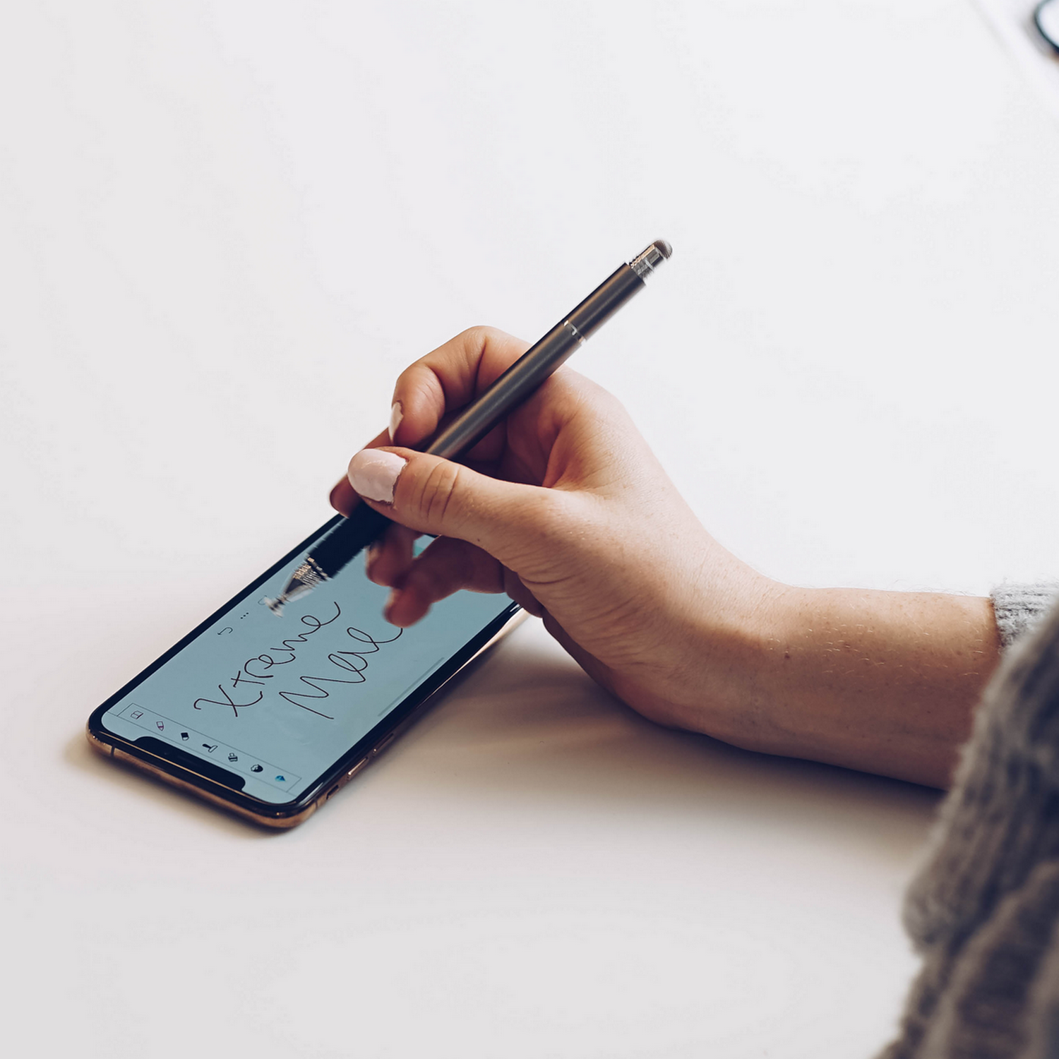 A hand is using a stylus to write on a smartphone screen, with the words "Xtreme Mail" visible.