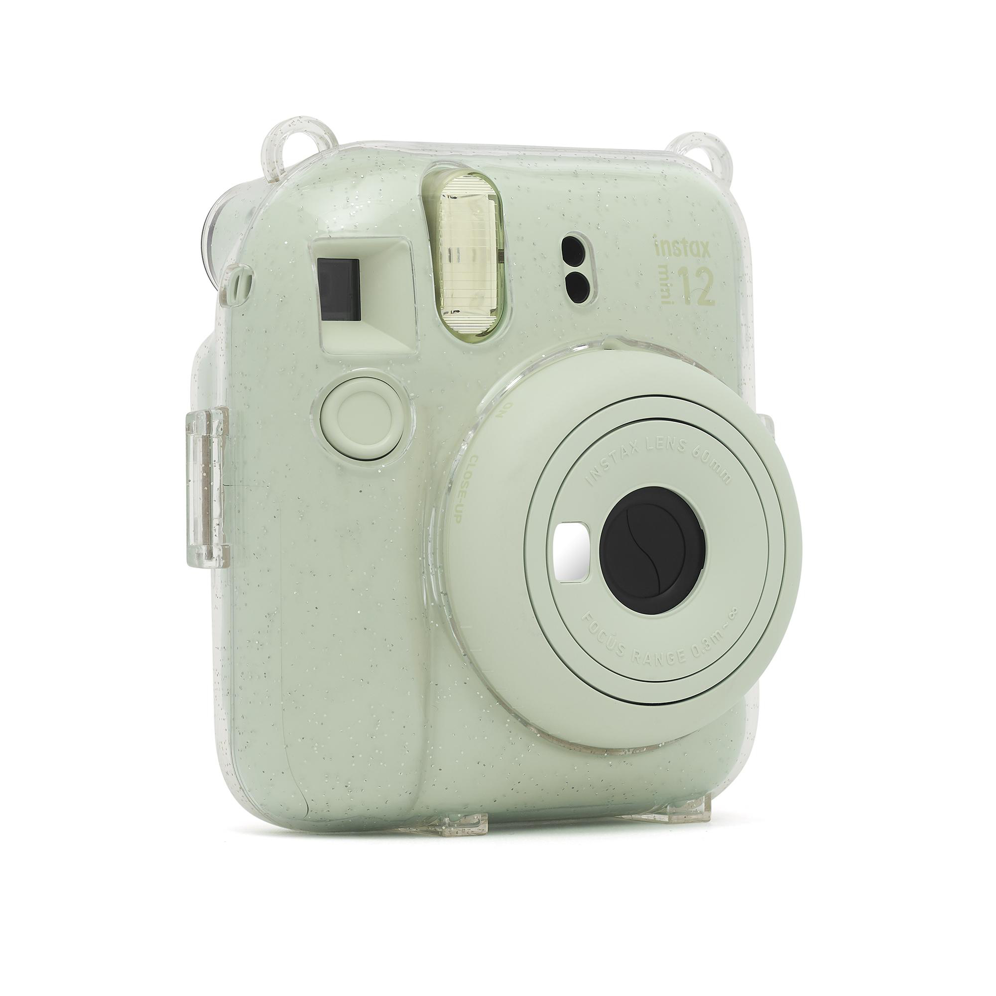 Eine grüne Instax-Kamera mit durchsichtiger Hülle, angewinkelt. Schwarzes Objektiv in der Mitte.