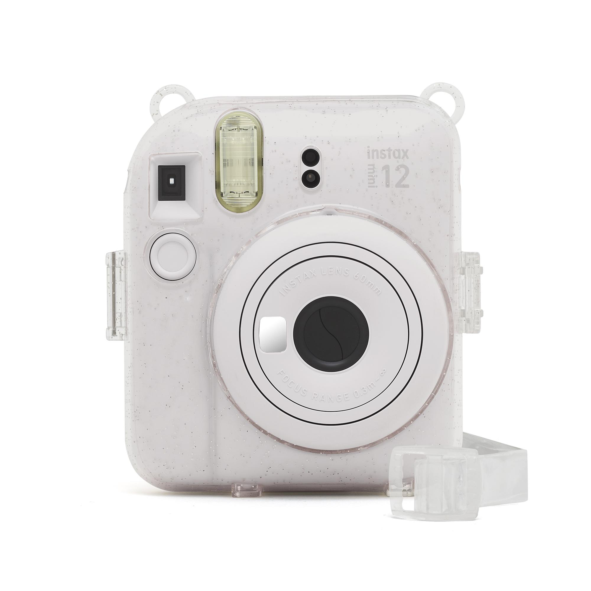 Weiße Instax Mini 12 Kamera. Sie hat ein Objektiv in der Mitte und einen Riemen. Das Gehäuse hat einen Glitzereffekt.
