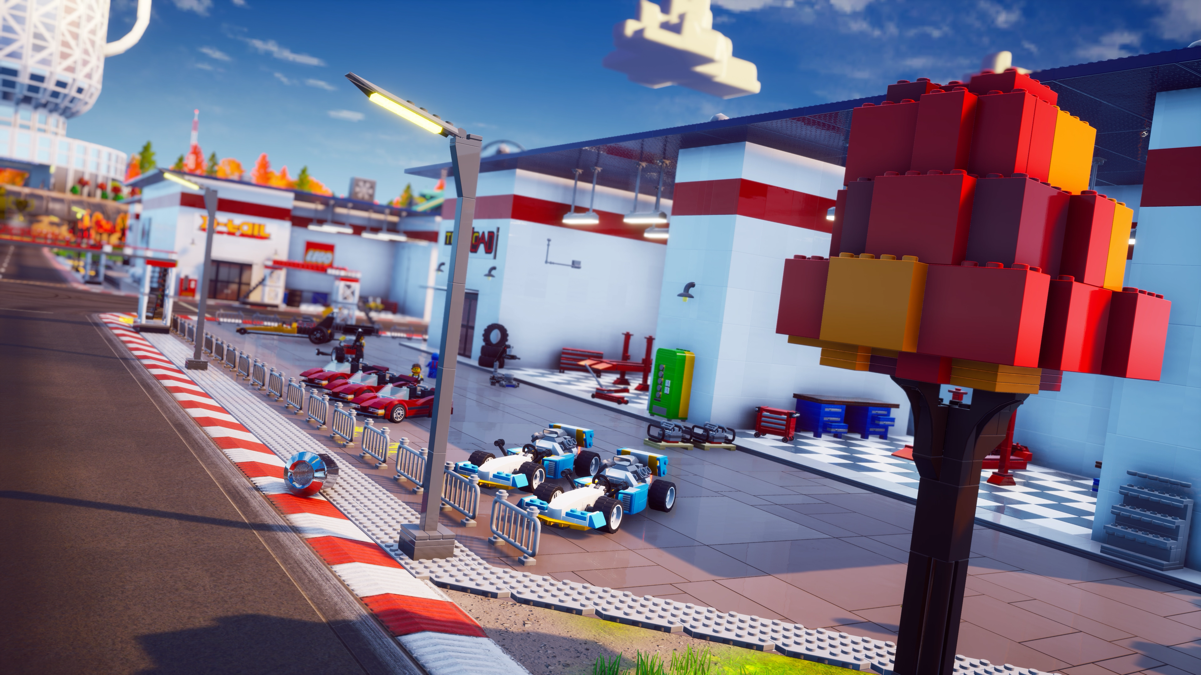 Scène de circuit de course de style Lego avec voitures, bâtiments et grande structure en briques.