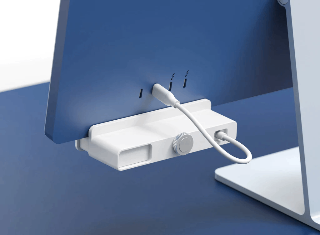 Vista trasera de un iMac azul con un concentrador de carga blanco. El fondo también es azul.
