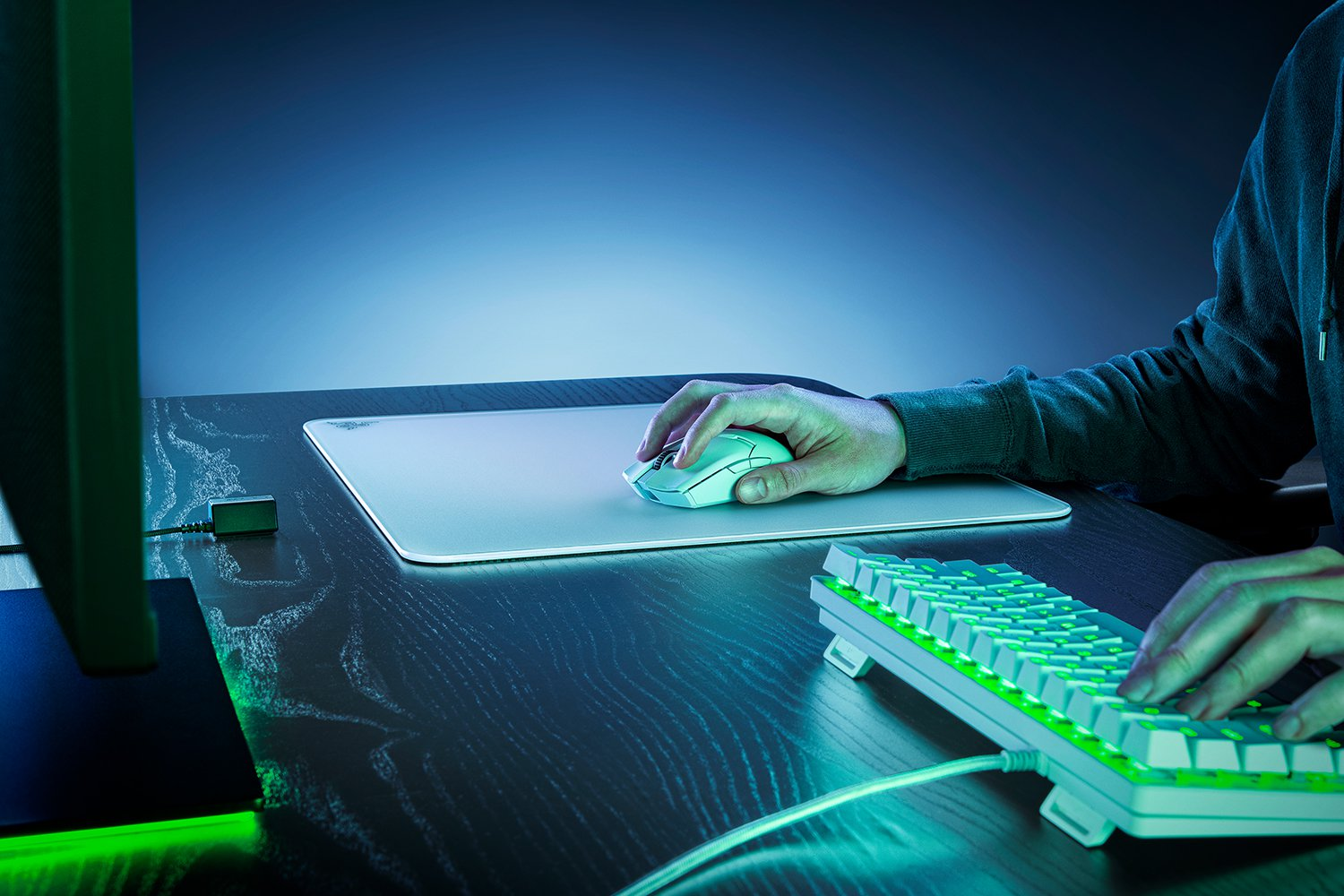 Spieler benutzt eine weiße Maus und Tastatur auf einem Schreibtisch mit blauem Hintergrund.