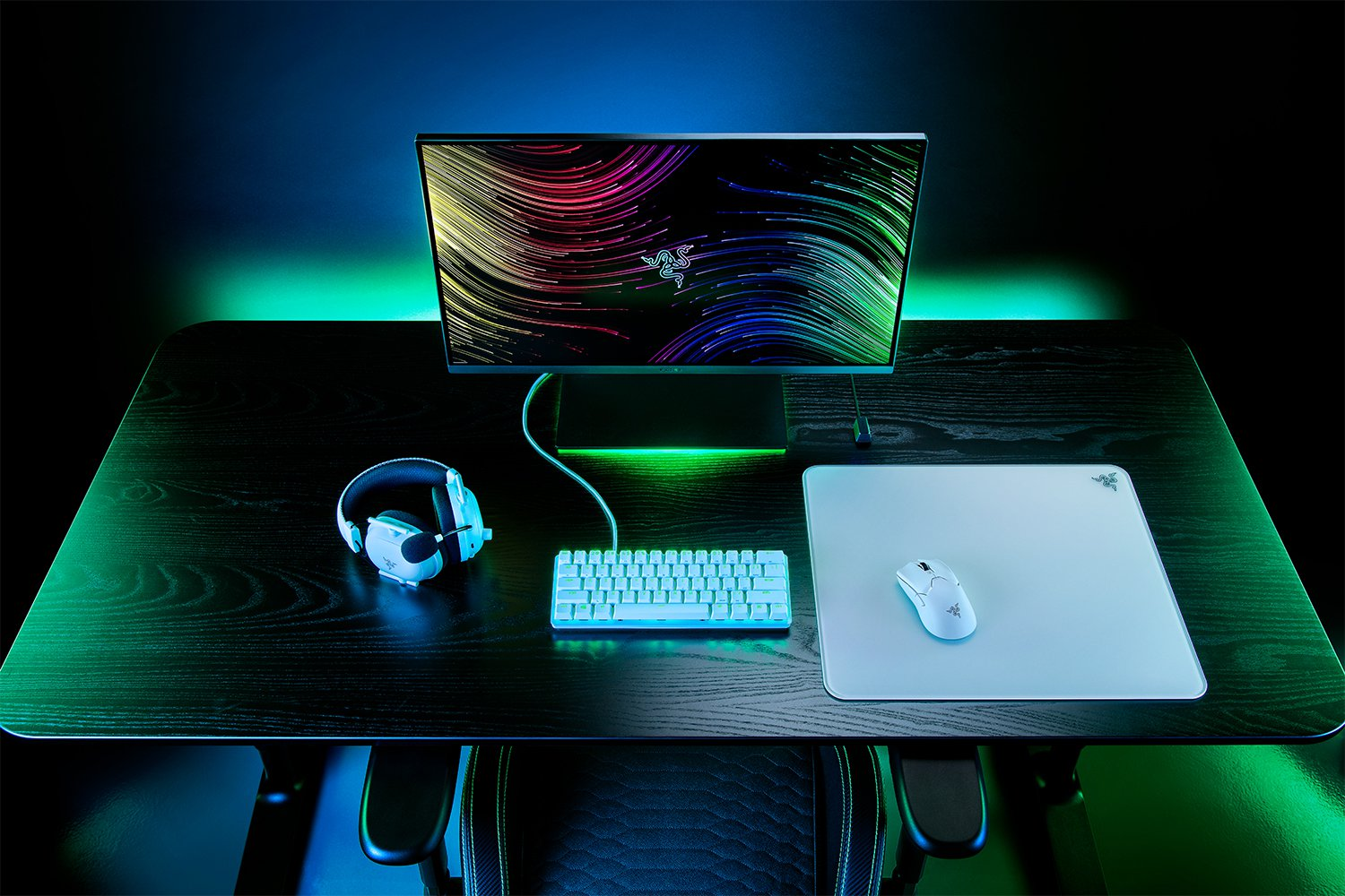 Schreibtisch-Setup mit Monitor, Tastatur, Maus und Headset. Dunkle Umgebung.