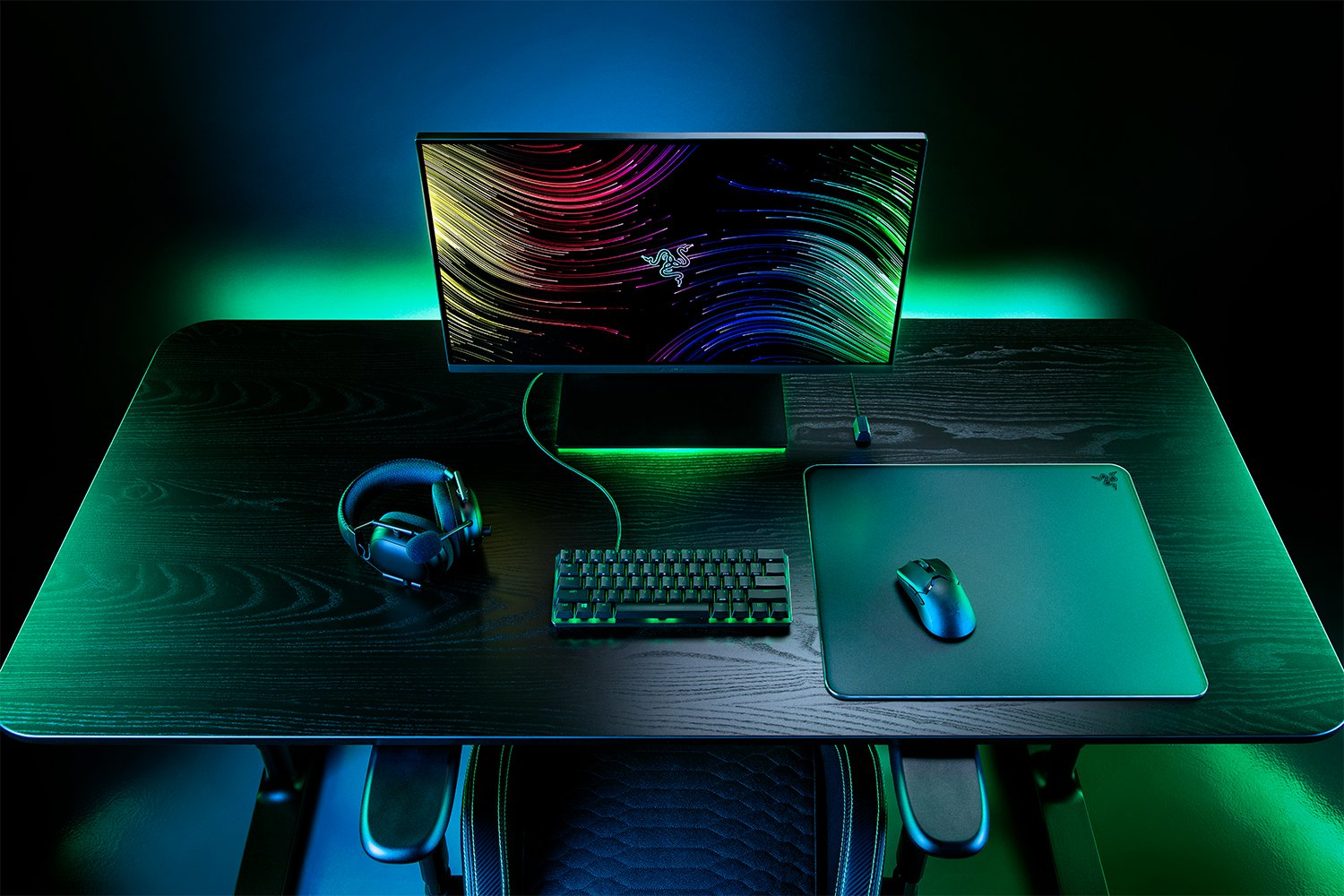 Configuration de jeu : moniteur, casque, clavier, souris sur bureau noir, lumières vertes.
