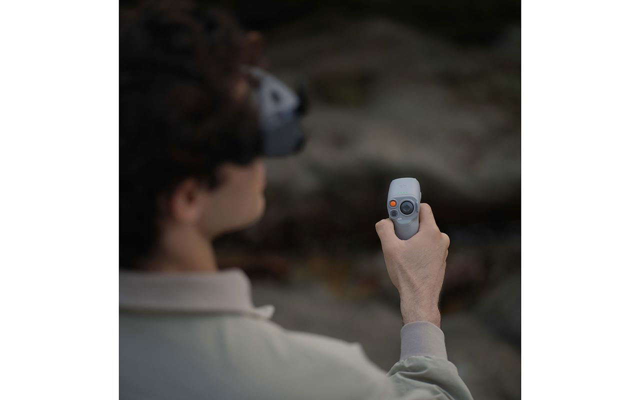 Person trägt ein VR-Headset und hält einen grauen Controller mit orangefarbenen und grauen Knöpfen.