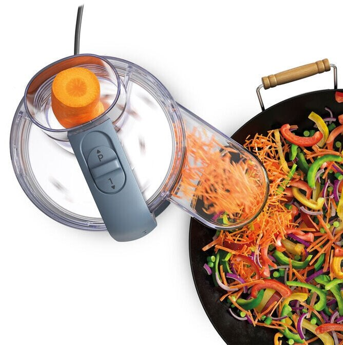 Robot kuchenny krojący marchewkę do patelni z smażonymi warzywami.