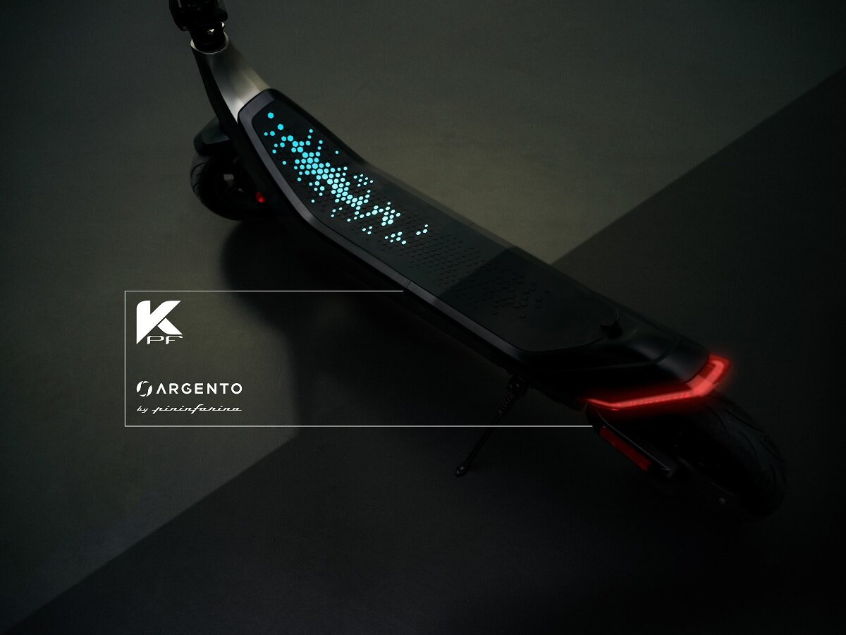 Czarna hulajnoga elektryczna z białym logo. Pokład ma wyświetlacz świetlny. Czerwone światło z tyłu.