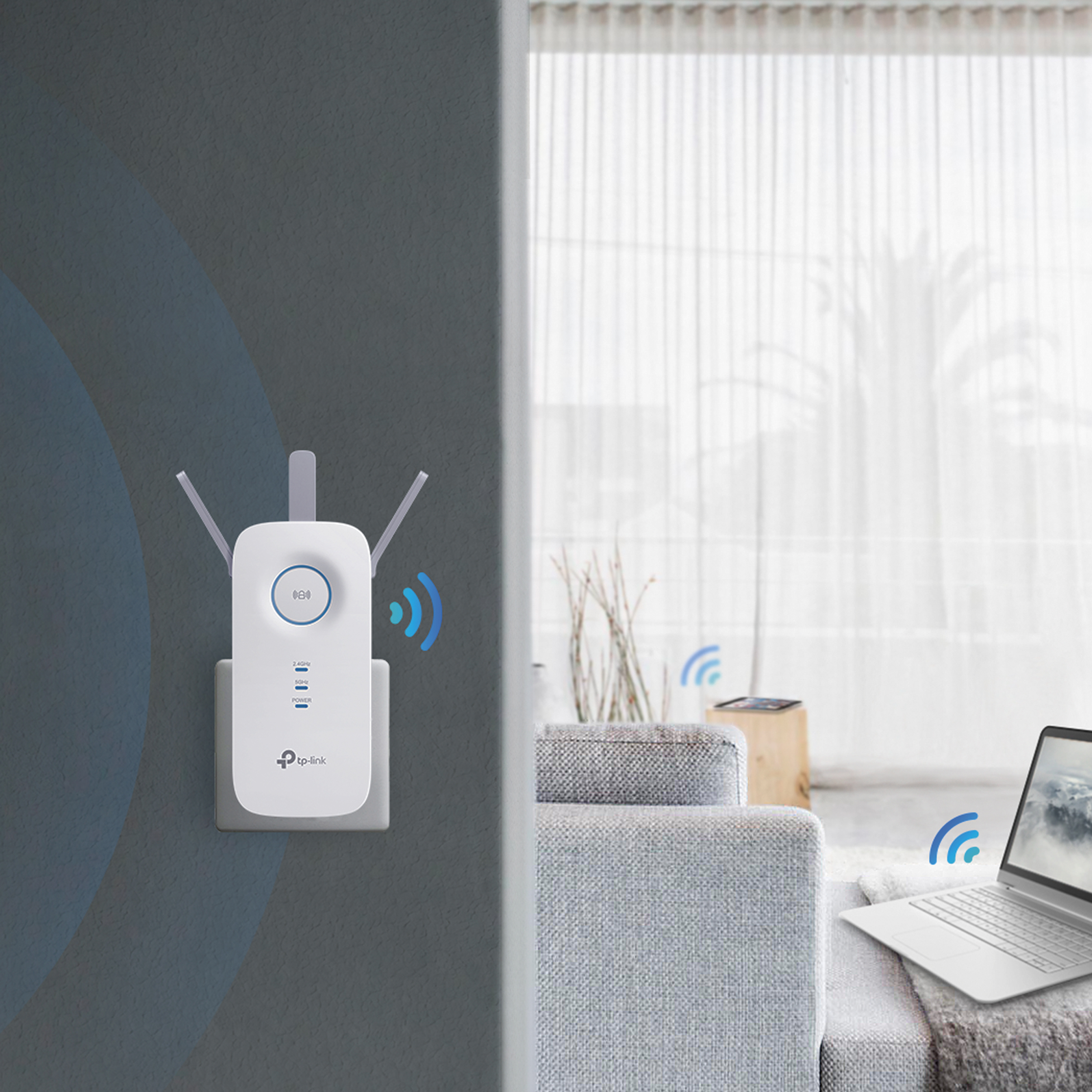 Extensor WiFi enchufado a la pared, con portátil y sofá al fondo.