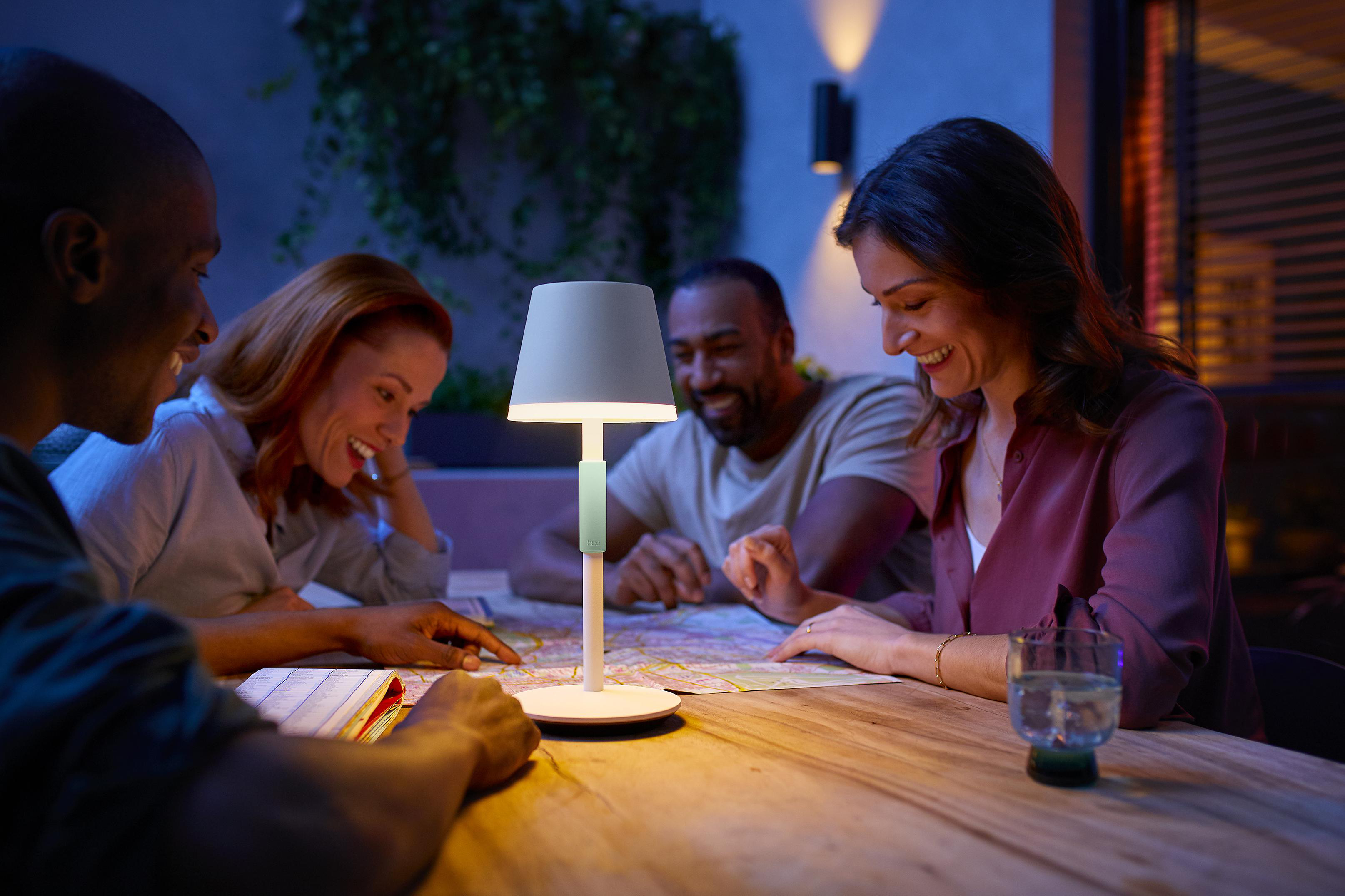 Vier Personen um einen Tisch mit einer Lampe, die nachts auf eine Karte schauen.