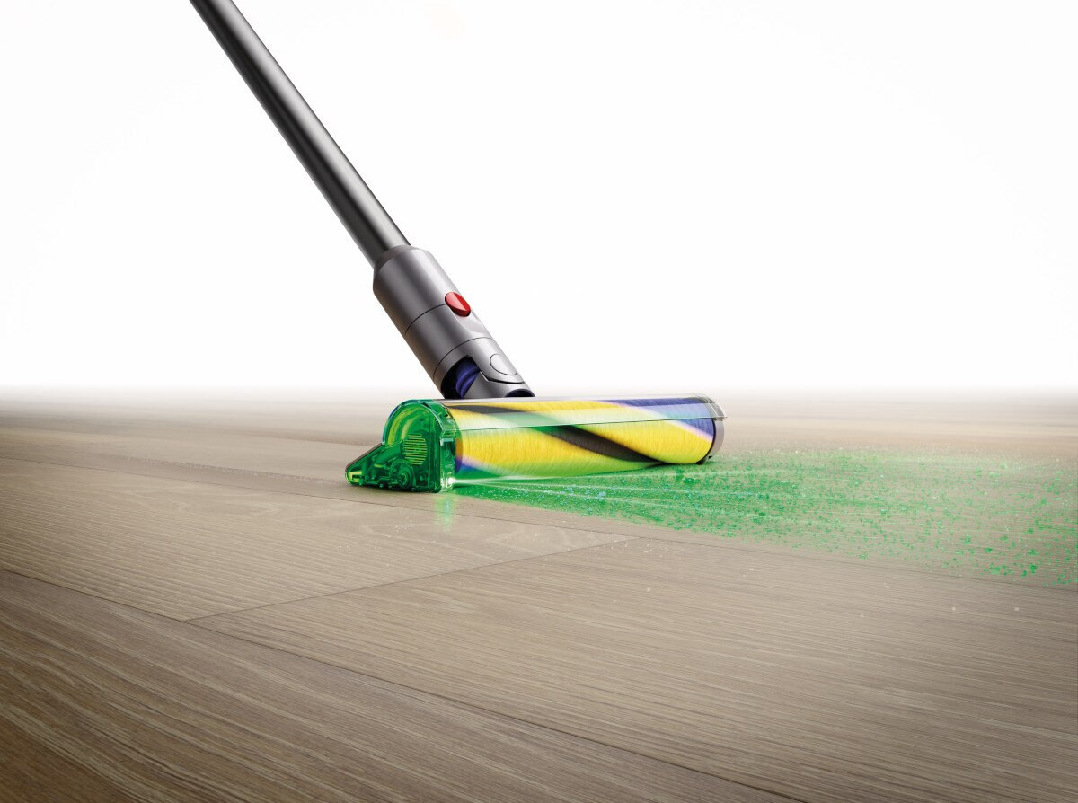 Głowica odkurzacza na podłodze. Zielone światło, żółta szczotka. Jasna podłoga drewniana. Jasnozielony ślad pyłu.