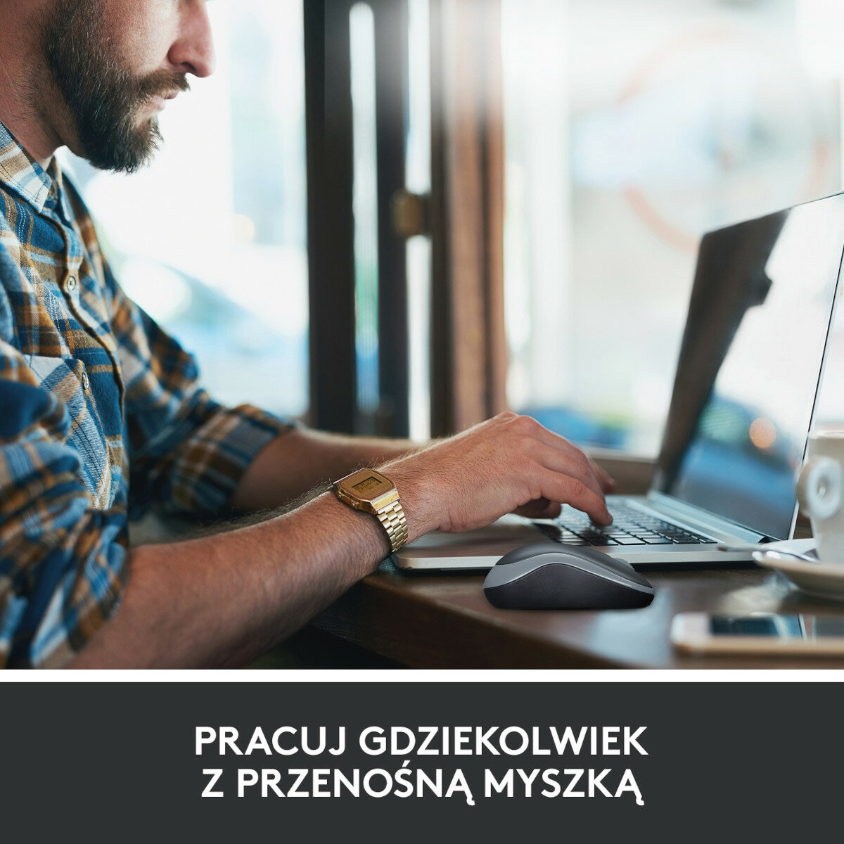 Mężczyzna używa laptopa z myszą bezprzewodową na drewnianym stole w kawiarni.