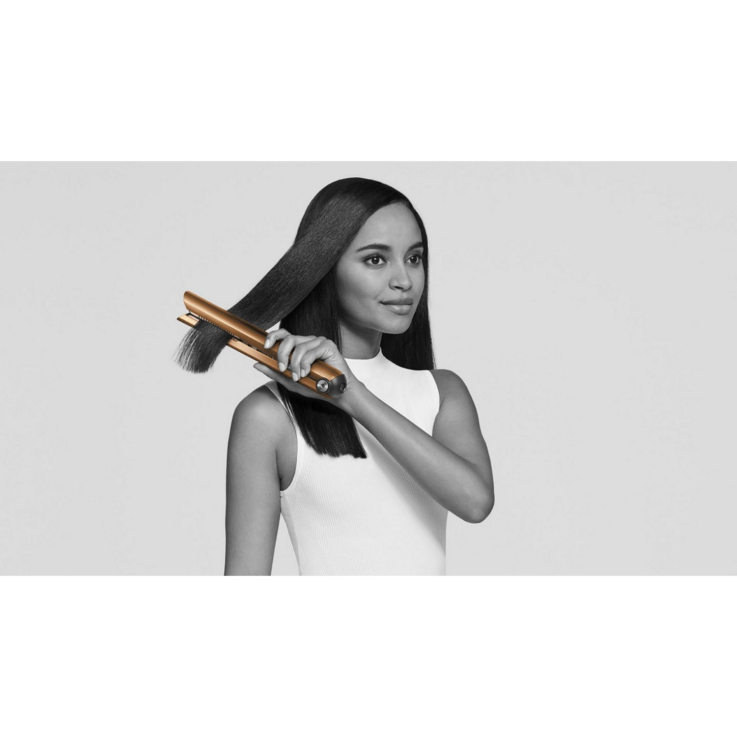 Woman using a gold hair straightener, straightening her hair.