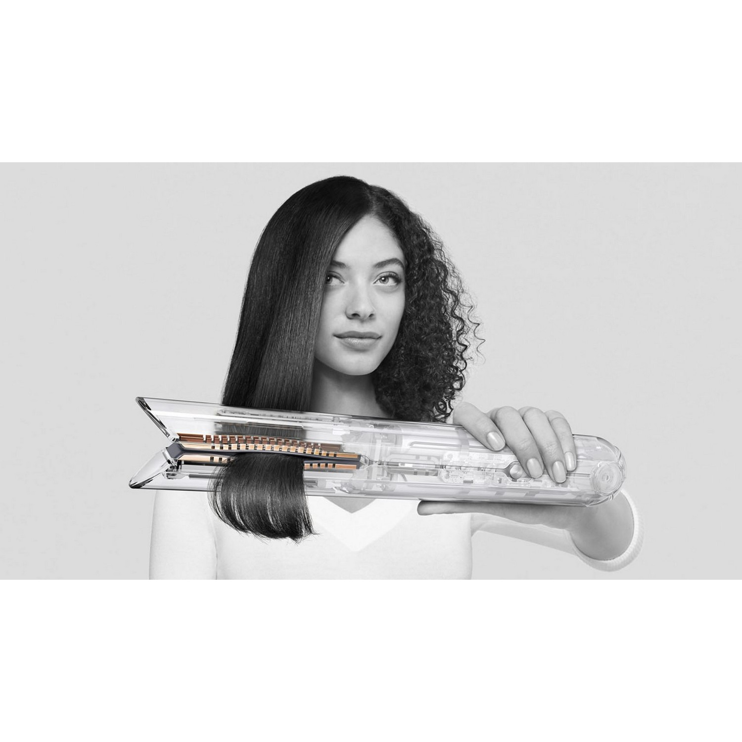 Woman with straight hair holding a hair straightener showing both straight and curly hair.