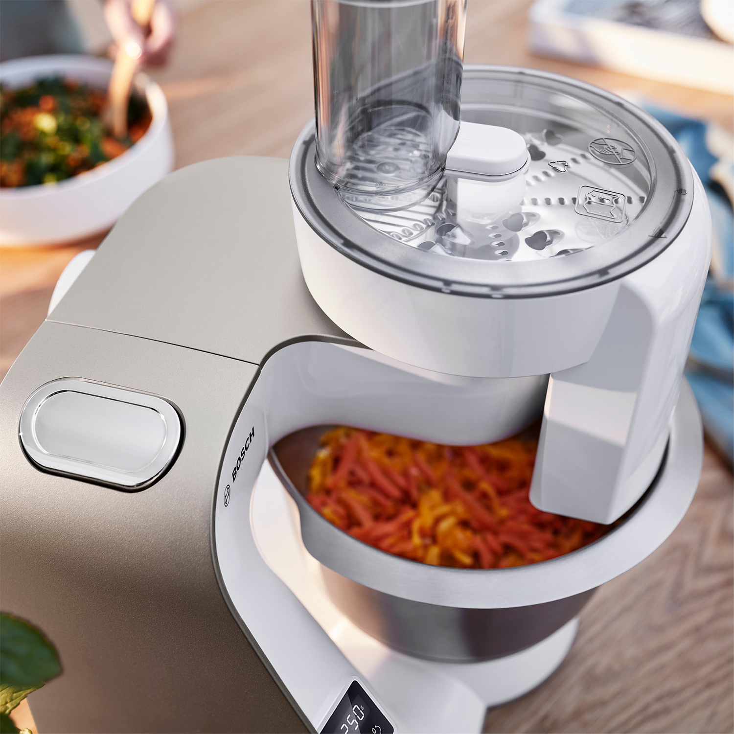 Robot da cucina Bosch con design bianco e grigio, e cibo all'interno.