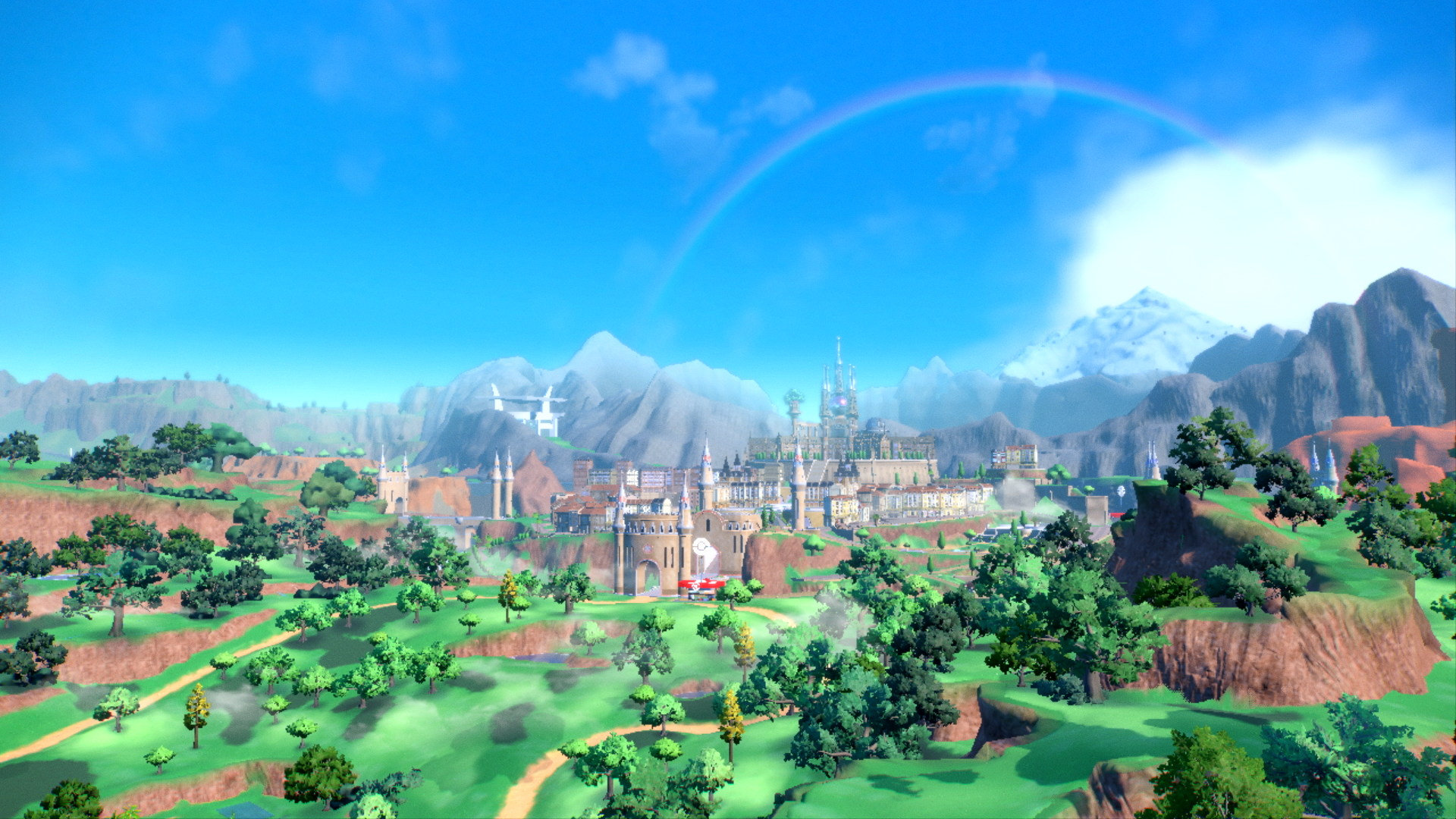 Landschap van een stad met een regenboog, bergen en groene velden.