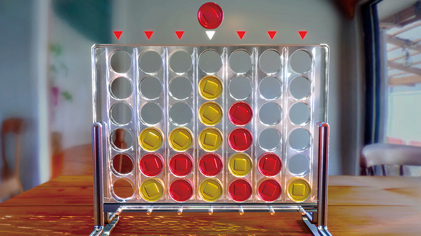 Een Connect Vier-spel staat op een houten tafel. Rode en gele fiches zitten in het transparante spelbord. Eén rode fiche staat op het punt om te vallen.