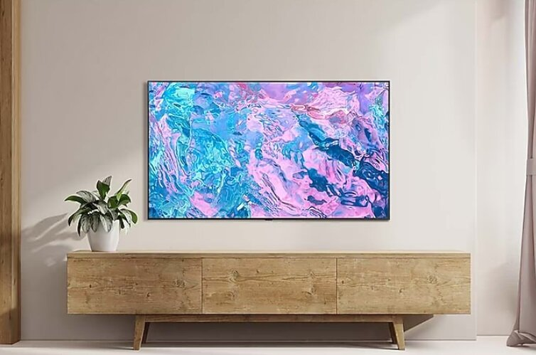 Telewizor z kolorową sztuką abstrakcyjną, na drewnianej szafce, z rośliną.