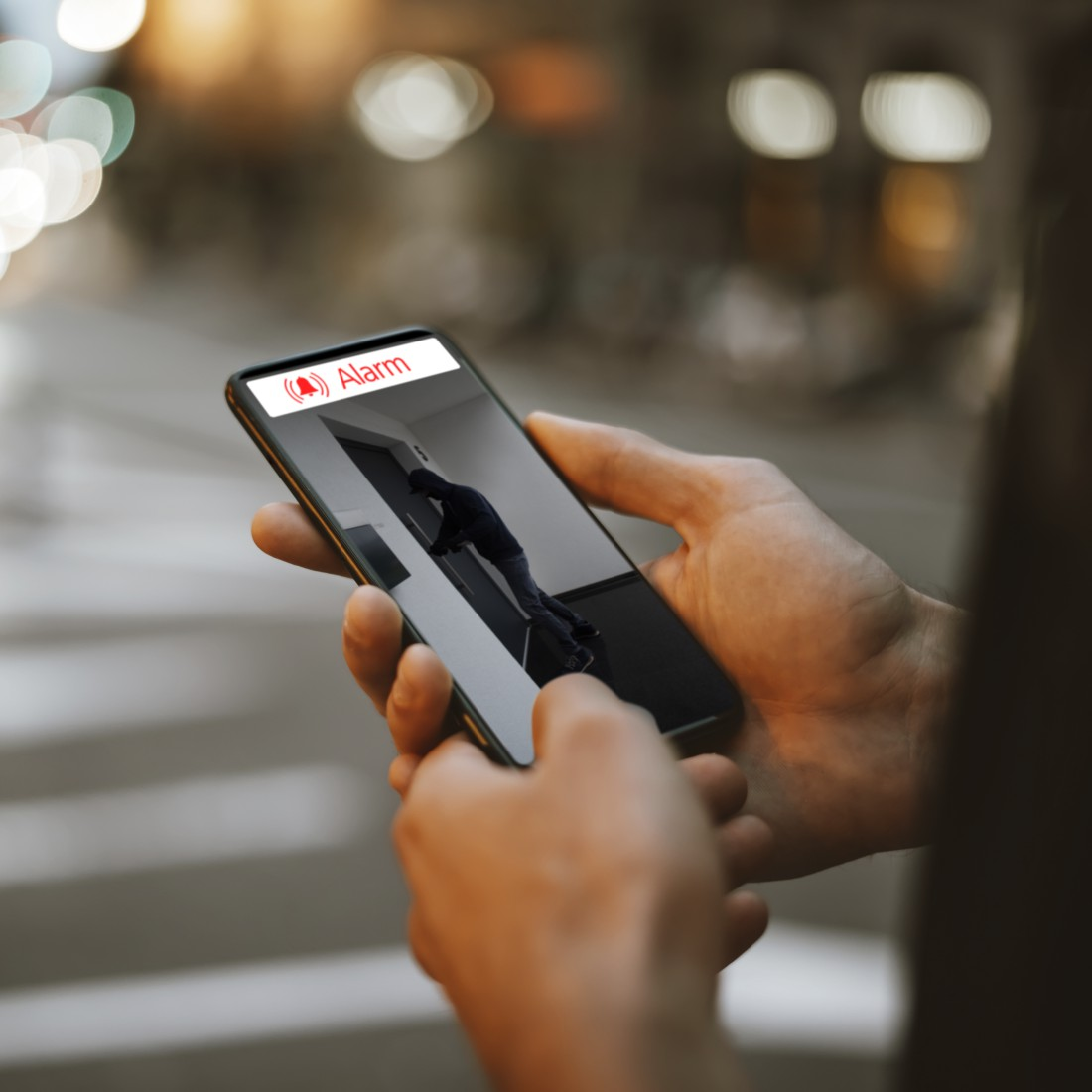 Eine Person hält ein Smartphone, das einen Sicherheitskamera-Feed anzeigt.
