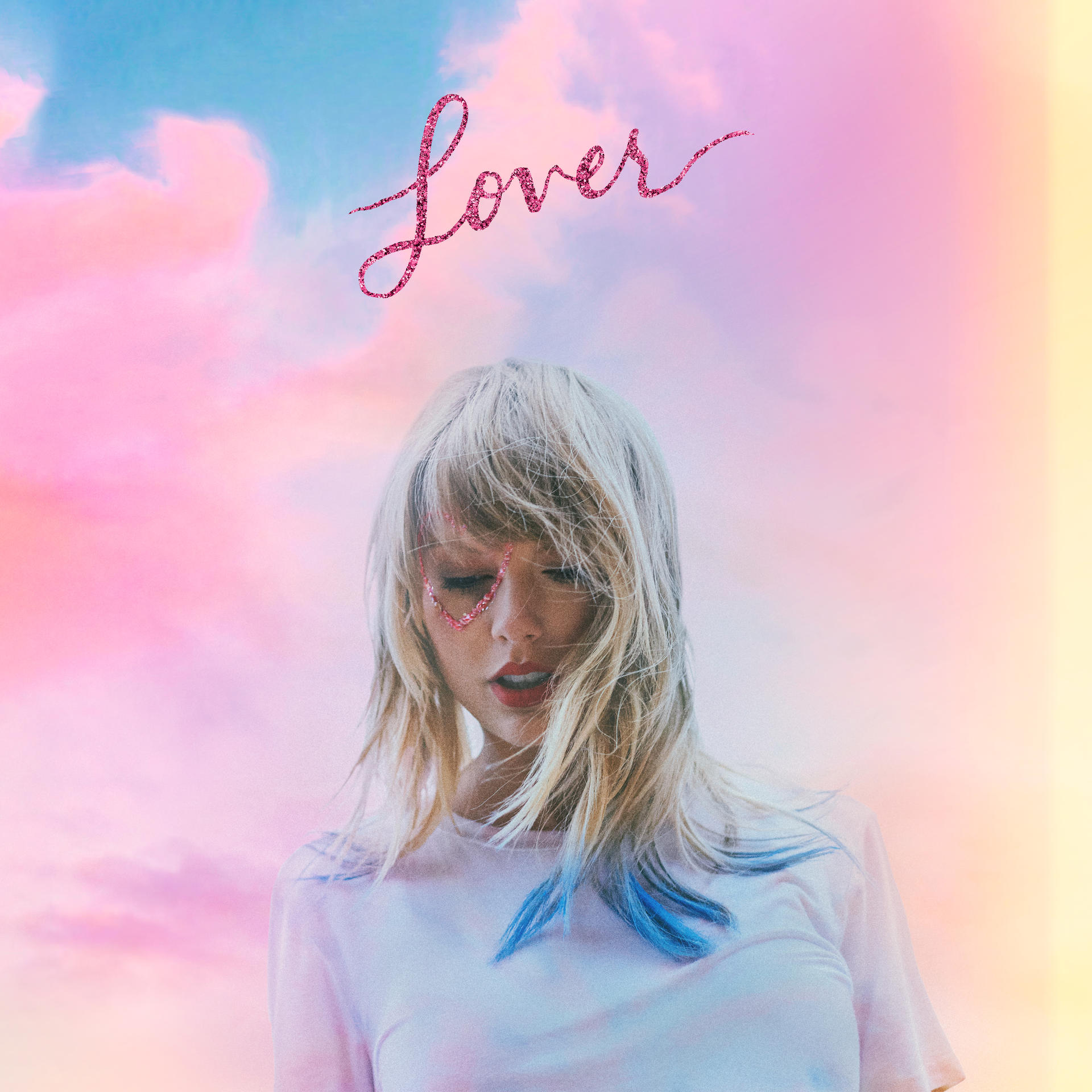 Taylor Swift mit pinkfarbenem Lover-Schriftzug. Sie trägt ein weißes Hemd und blaue Strähnen im Haar.