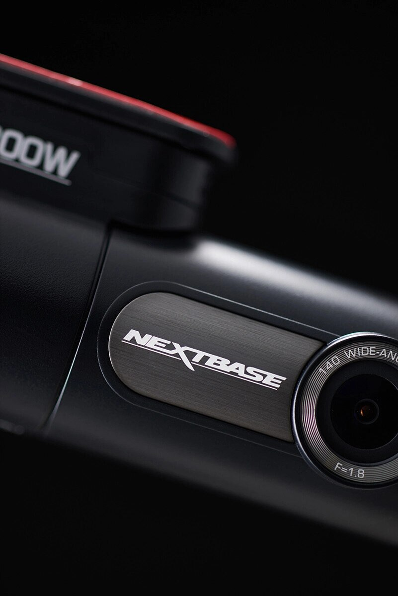 Zbliżenie czarnej kamery samochodowej. Widoczne logo Nextbase, obiektyw po prawej.