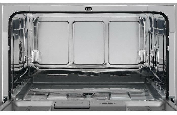 Widok wnętrza pustej zmywarki, z widocznymi koszami i ramionami natryskowymi.