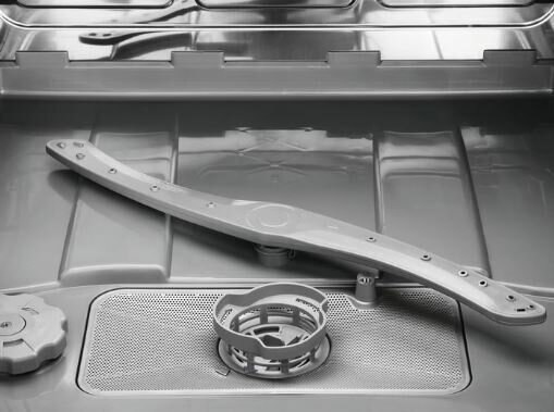 Wnętrze zmywarki: ramię natryskowe, filtr i wlot wody, wszystko szare.