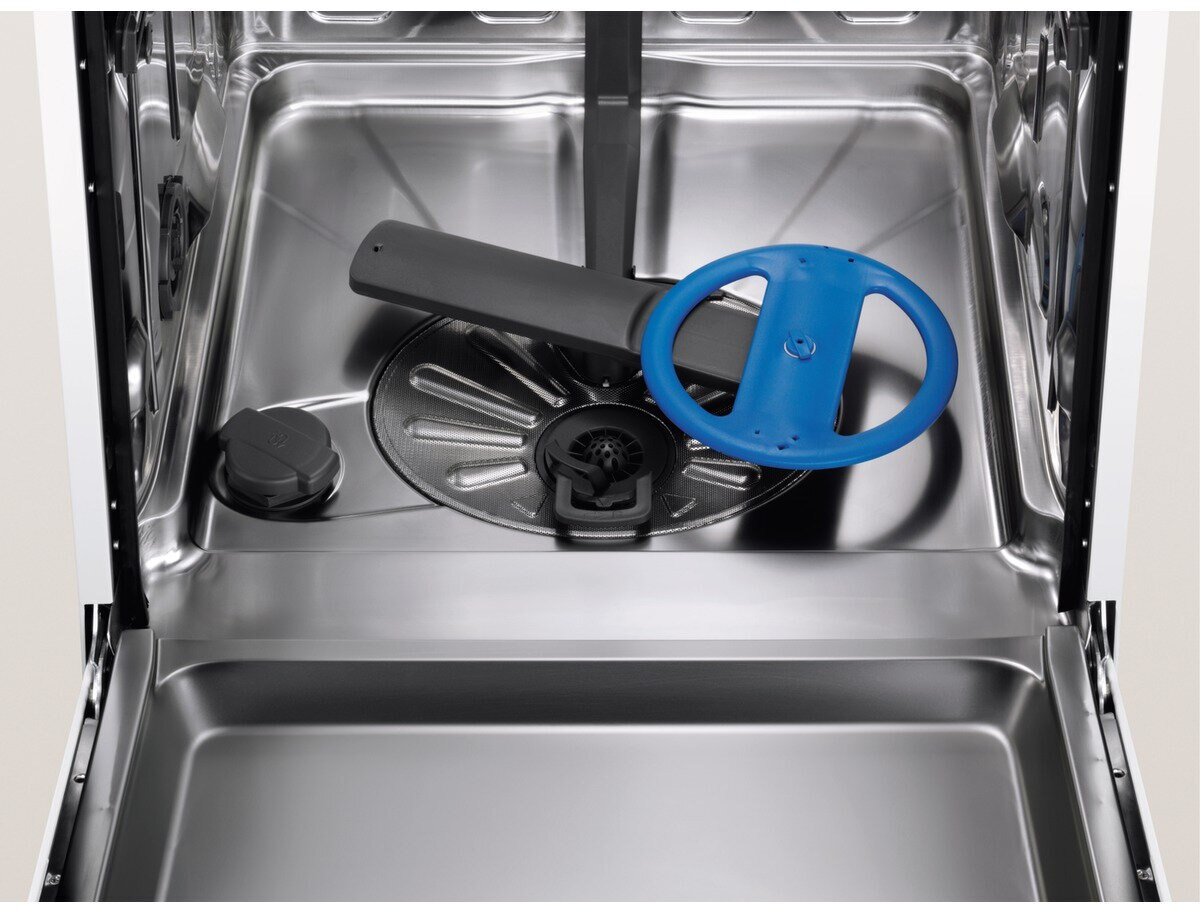 Wnętrze zmywarki z niebieskim ramieniem natryskowym i filtrem. Wnętrze ze stali nierdzewnej.