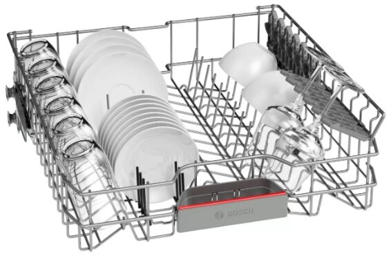 Kosz zmywarki, pełen talerzy, szklanek i filiżanek, w środku. Kosz jest metalowy, z szarym uchwytem.