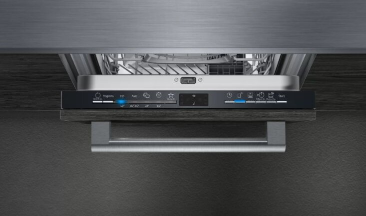 Panel sterowania zmywarki z przyciskami i wyświetlaczem. Uchwyt ze stali nierdzewnej poniżej. Ciemne drewno i szare tło.