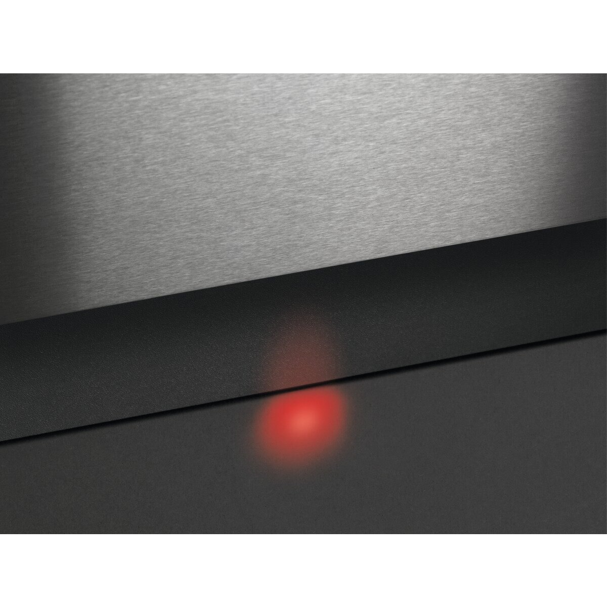 Zbliżenie czarnego panelu urządzenia z czerwoną lampką. Nad nim znajduje się stalowy panel.