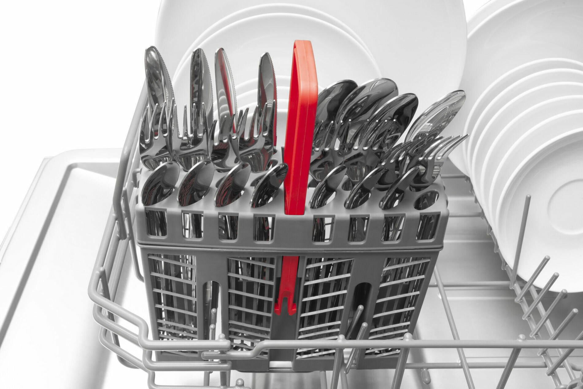 Kosz na sztućce z srebrnymi sztućcami i czerwonym uchwytem w zmywarce.