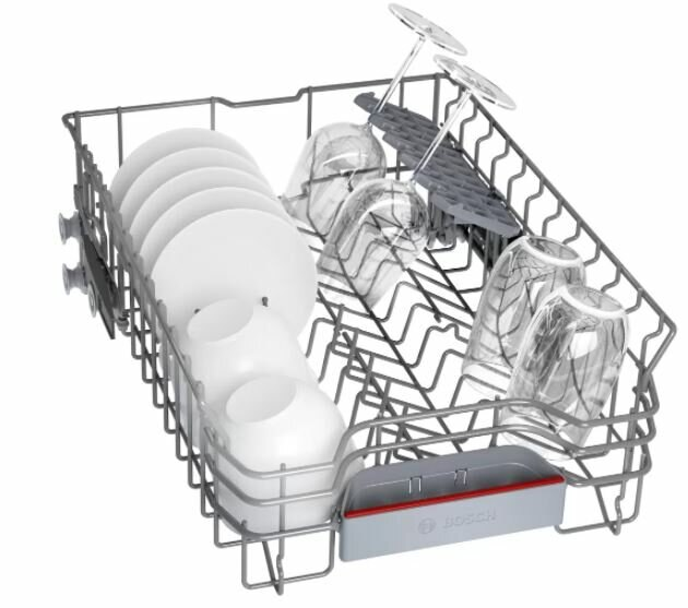 Dolny kosz zmywarki załadowany talerzami, filiżankami i szklankami.