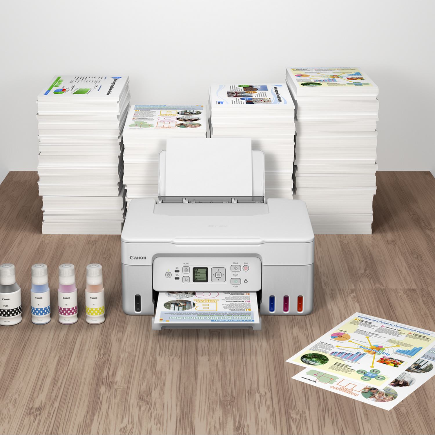 A white Canon printer with printed documents, stacks of paper, and ink cartridges on a table.