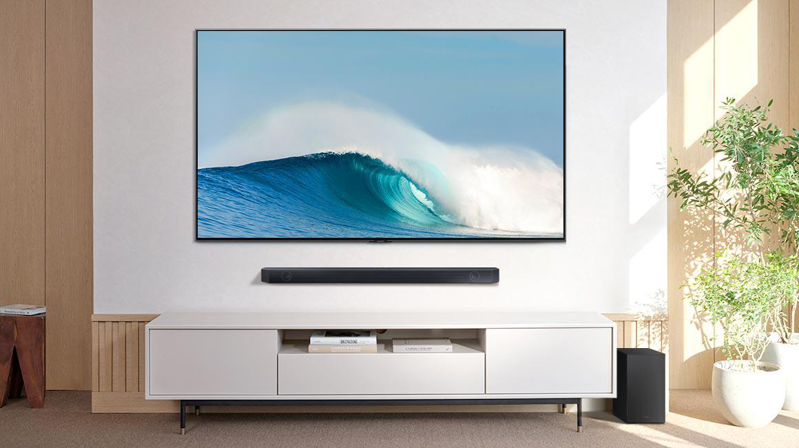 Wohnzimmer mit TV-Welle, Soundbar, weißem Schrank und Pflanzen.