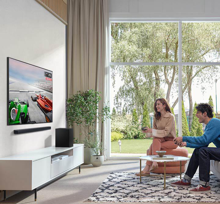Ein Wohnzimmer mit einem Fernseher, der ein Rennen zeigt, und einem Paar auf einem Sofa.