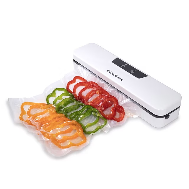 Sellador al vacío con pimientos rojos, verdes y naranjas en bolsas selladas al vacío, sobre blanco.