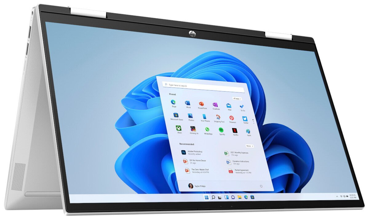 Srebrny laptop z ekranem pokazującym interfejs Windows, otwarty pod kątem. Tło to biała powierzchnia.