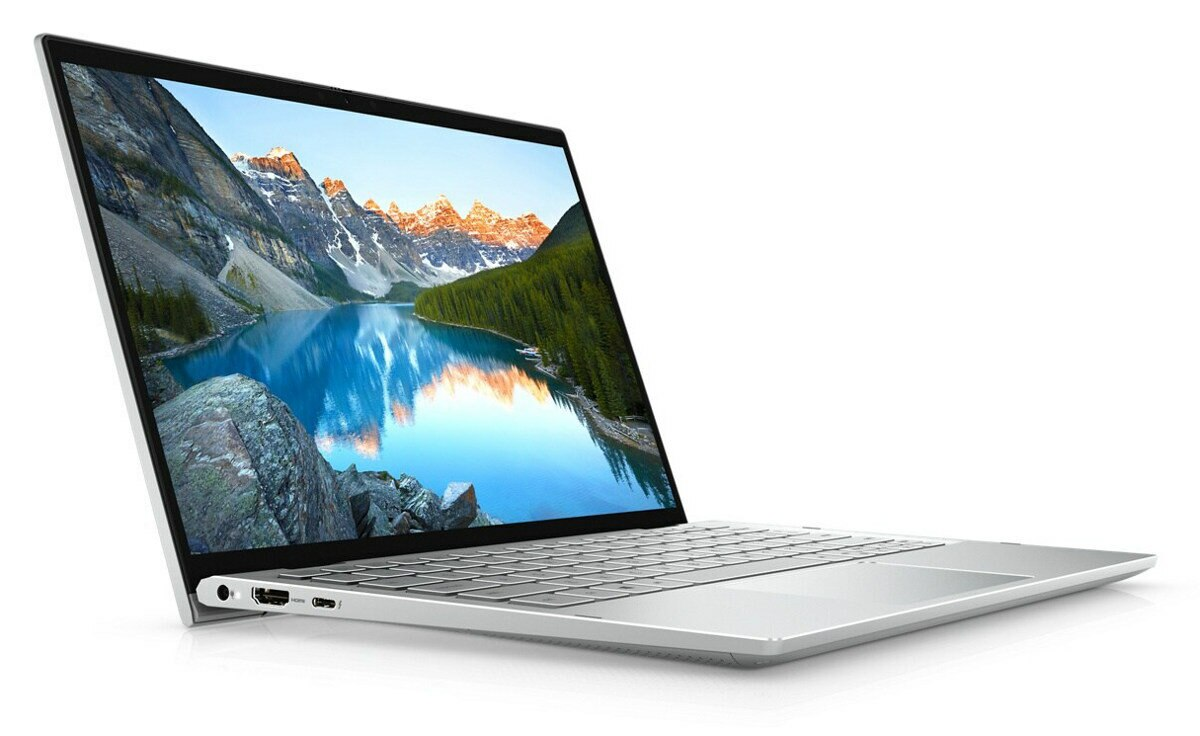 Srebrny laptop otwarty, pokazujący malowniczy widok na góry, jezioro i zielone drzewa.