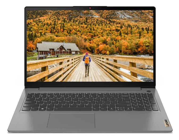 Laptop wyświetla most nad rzeką z osobą idącą. Jesienne kolory w tle.