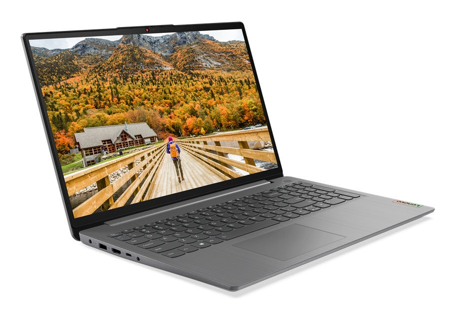 Otwarty szary laptop Lenovo na moście, wyświetlający widok osoby idącej w kierunku budynku w tle.