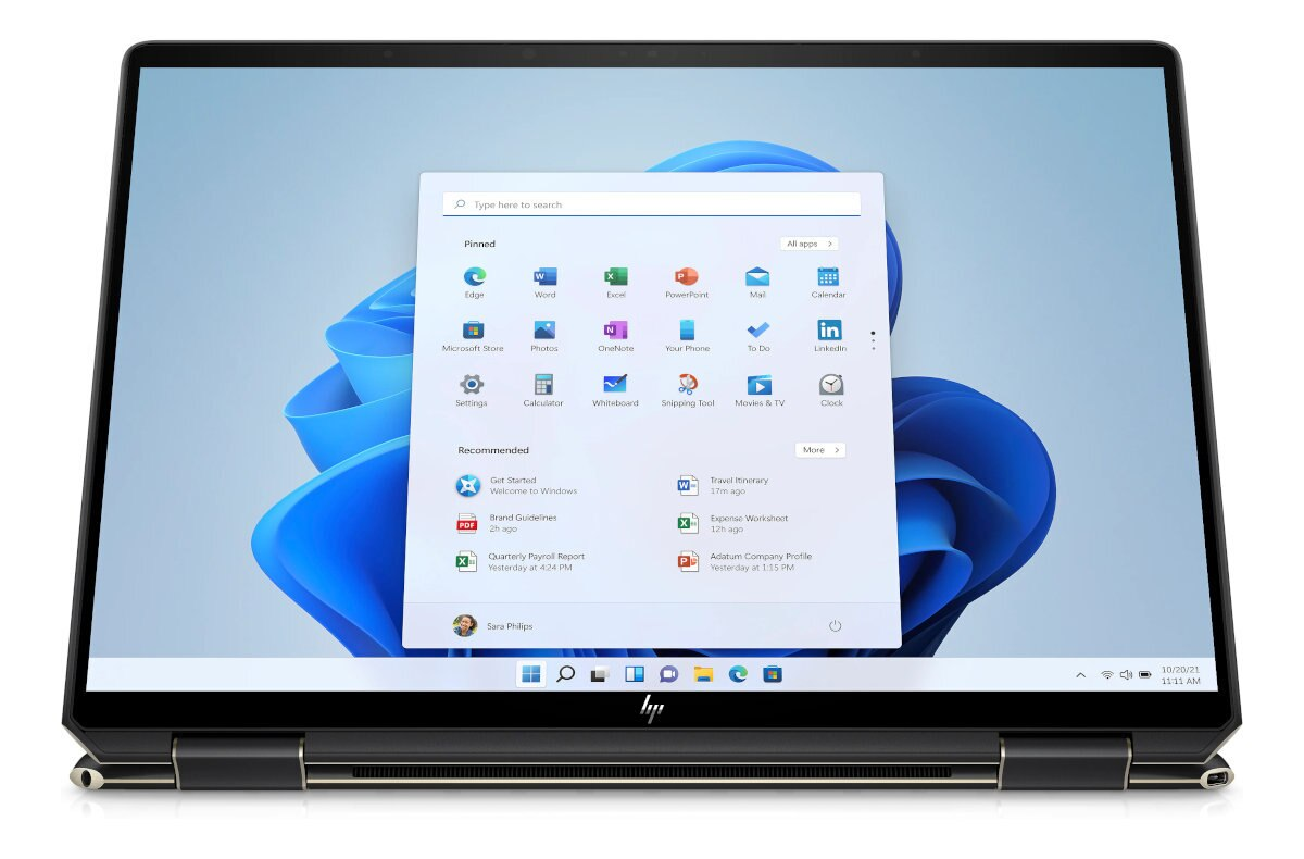 Laptop z otwartym interfejsem Windows 11, pokazujący przypięte aplikacje. Czarna ramka.