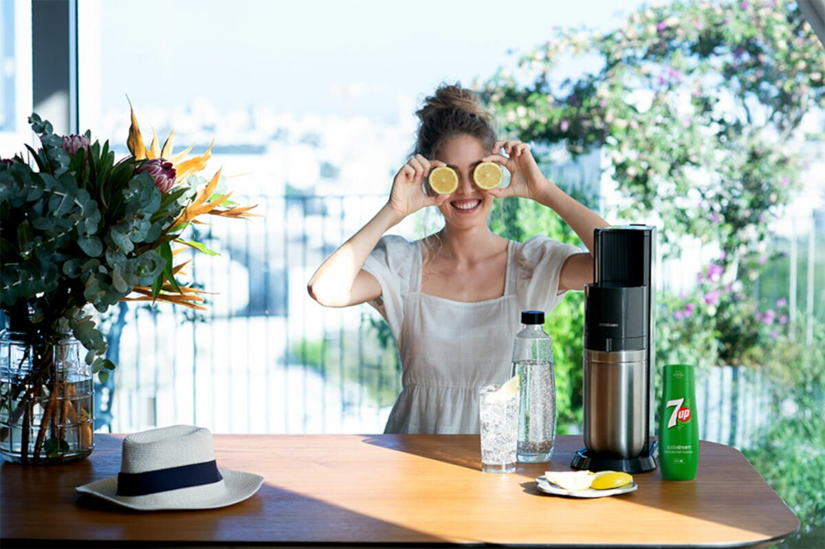 Kobieta trzymająca plasterki cytryny nad oczami, uśmiechnięta do kamery.