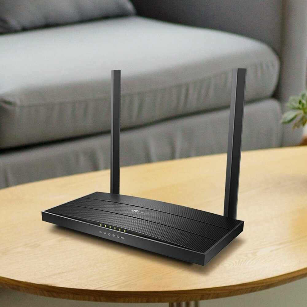 Czarny router z dwiema antenami stojący na drewnianym stole.