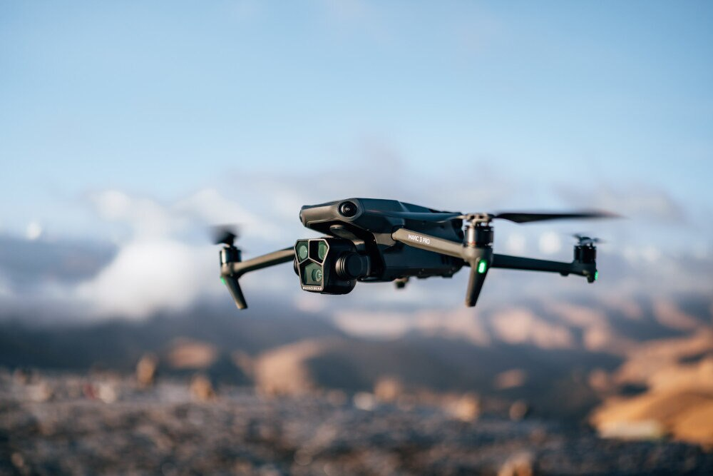 Dron w powietrzu, rozmyte tło wzgórz i nieba.