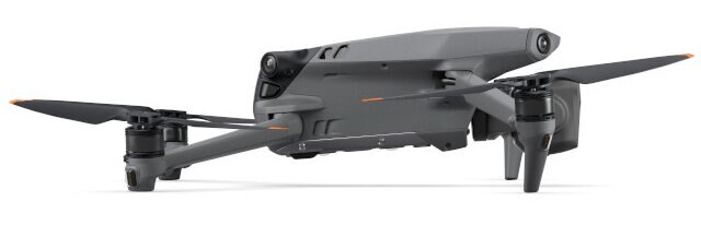 Szary dron z czarnymi śmigłami.