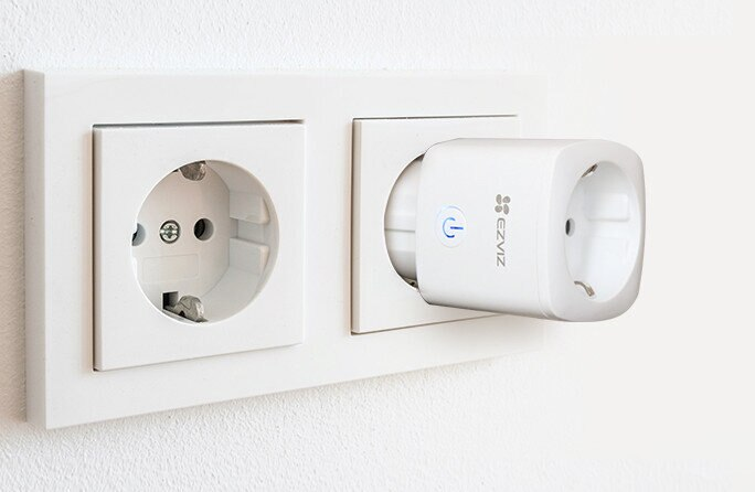 Biała ściana z dwoma gniazdkami. Jedno ma włożoną inteligentną wtyczkę.
