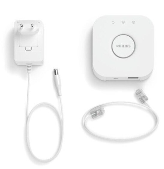 Biały zestaw urządzeń smart home Philips: mostek, zasilacz i kabel sieciowy.